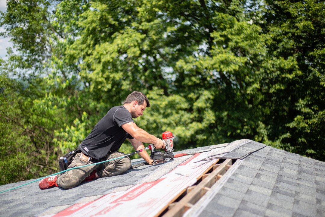 A man sits on the roof and fixes the trim