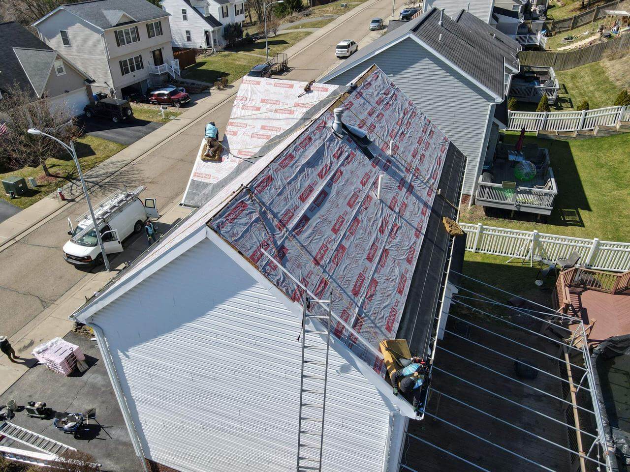 two men are covering the roof of a house