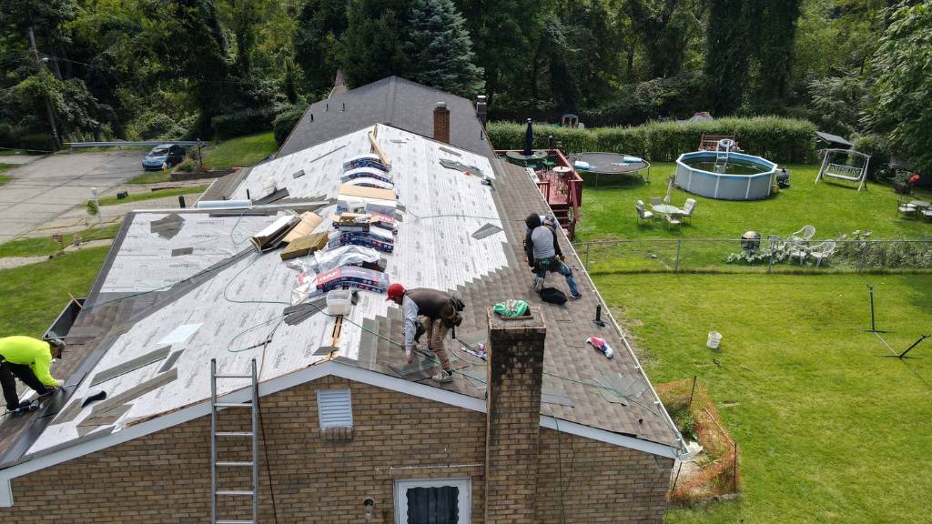 Professional roofers installing roofing shingles on top of roofing underlayment.