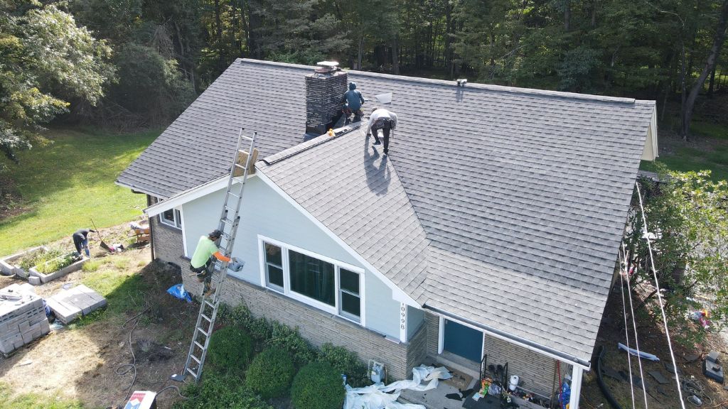 A roof with professional workers replacing the roof, ensuring maintenance and longevity.